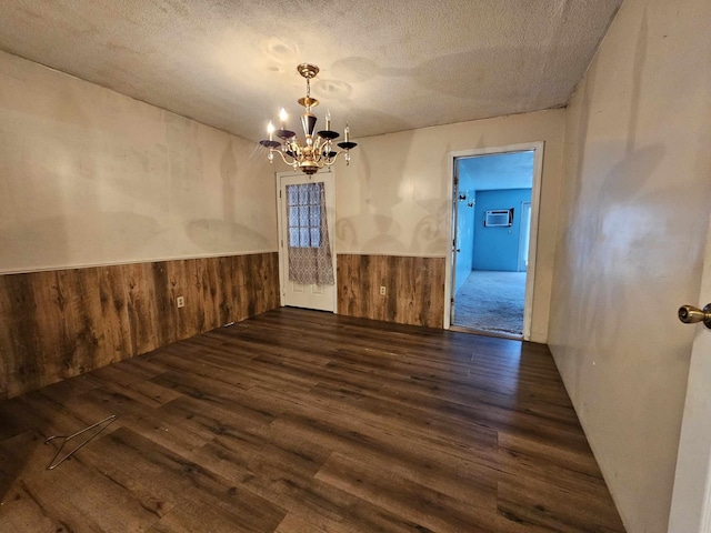 empty room featuring a textured ceiling, dark hardwood / wood-style flooring, and a notable chandelier