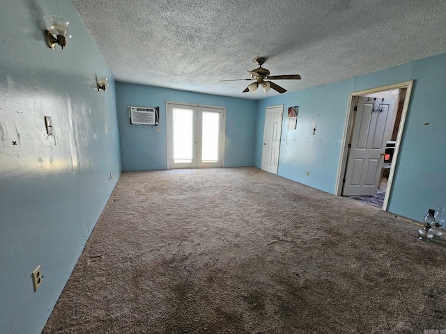 carpeted empty room featuring ceiling fan, an AC wall unit, french doors, and a textured ceiling