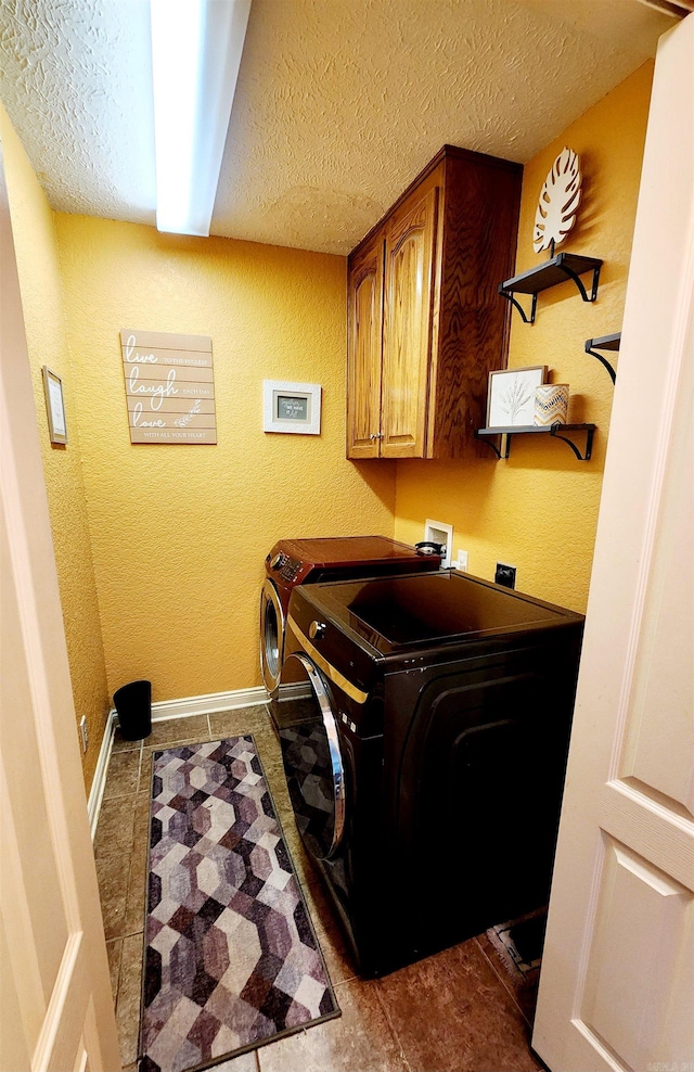 laundry room with cabinets, a textured ceiling, tile patterned flooring, and washing machine and dryer