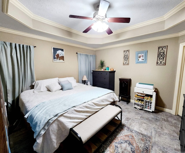 bedroom with ceiling fan, a textured ceiling, a raised ceiling, and ornamental molding