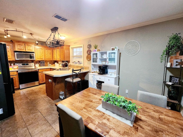 kitchen featuring tasteful backsplash, an island with sink, a kitchen bar, appliances with stainless steel finishes, and crown molding