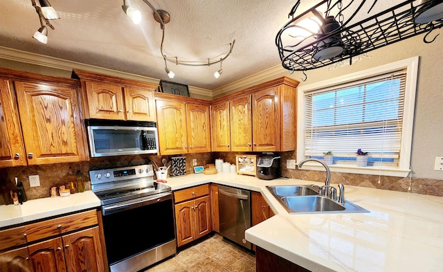 kitchen featuring appliances with stainless steel finishes, decorative backsplash, a textured ceiling, crown molding, and sink