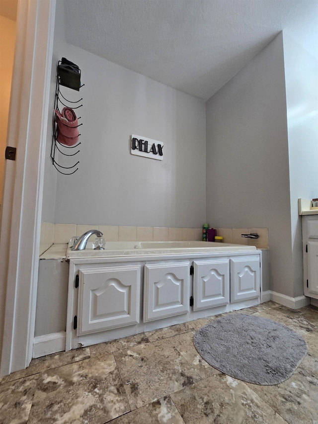 bathroom with a tub to relax in, a textured ceiling, and vanity