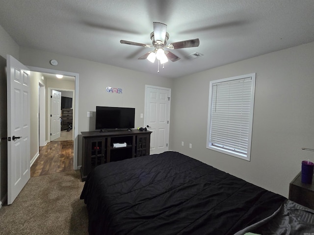 bedroom featuring a textured ceiling, dark carpet, and ceiling fan