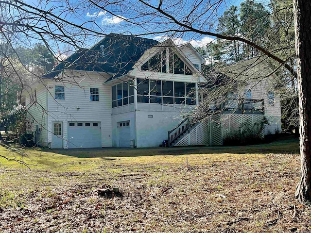 exterior space featuring a lawn, a garage, and a sunroom