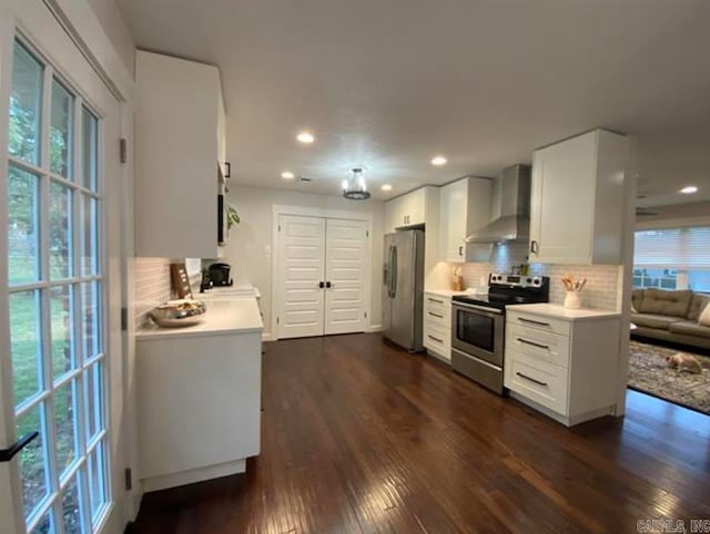 kitchen featuring decorative backsplash, white cabinets, wall chimney exhaust hood, stainless steel appliances, and dark hardwood / wood-style floors