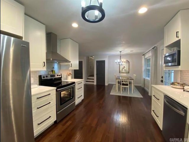 kitchen featuring wall chimney range hood, stainless steel appliances, and white cabinets