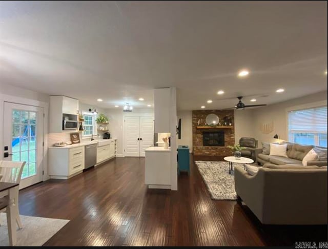 living room with a fireplace, dark hardwood / wood-style floors, and ceiling fan