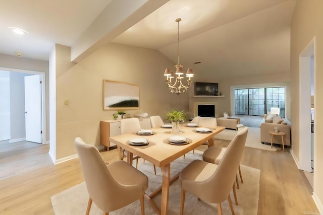 dining area with light hardwood / wood-style flooring, vaulted ceiling, and a chandelier