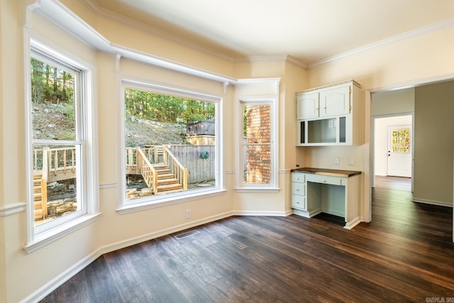 interior space with baseboards, visible vents, dark wood-style floors, ornamental molding, and built in desk