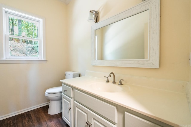 half bathroom featuring wood finished floors, vanity, toilet, and baseboards