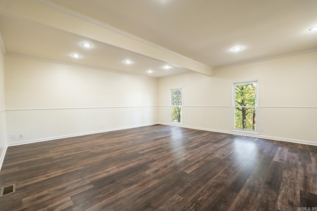 empty room featuring recessed lighting, dark wood-type flooring, visible vents, ornamental molding, and wainscoting