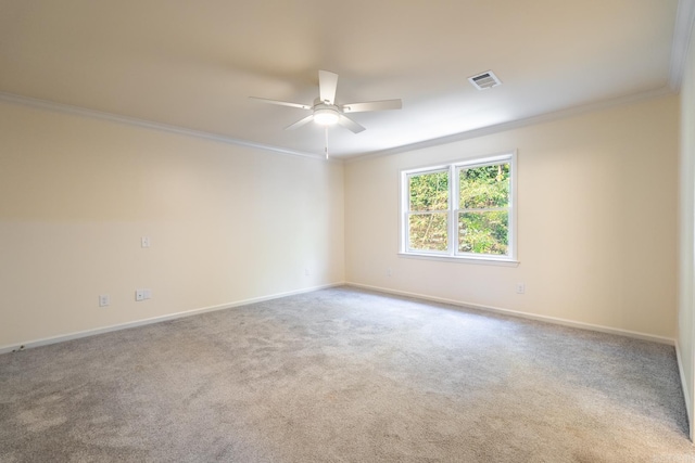 carpeted spare room featuring baseboards, ceiling fan, visible vents, and crown molding