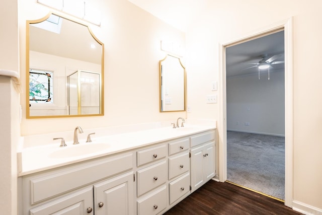 full bathroom with wood finished floors, a sink, baseboards, and double vanity