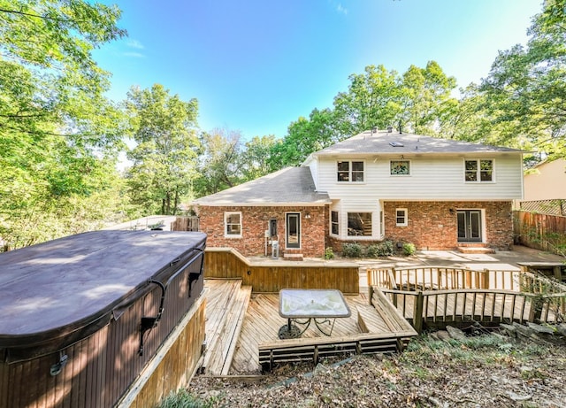 rear view of house with a deck, brick siding, fence, french doors, and a hot tub