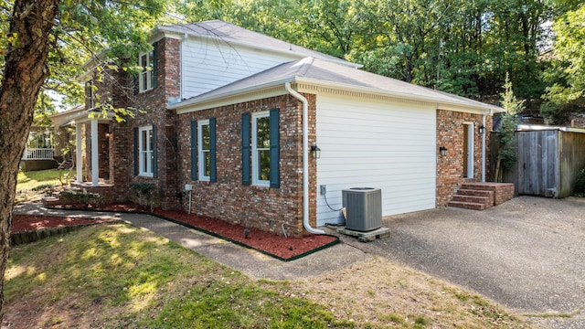 view of property exterior featuring central air condition unit, fence, and brick siding