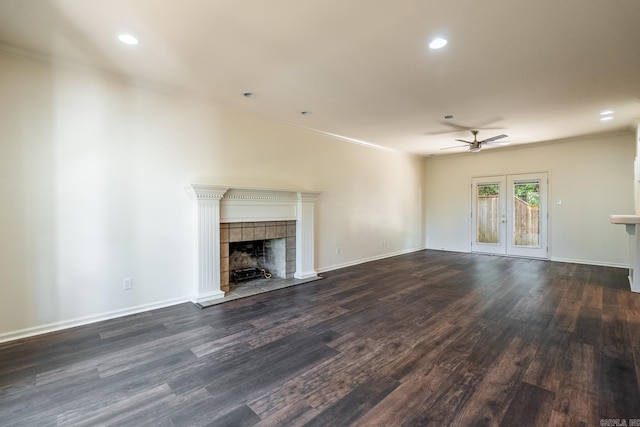 unfurnished living room featuring french doors, dark wood-type flooring, a tile fireplace, and baseboards