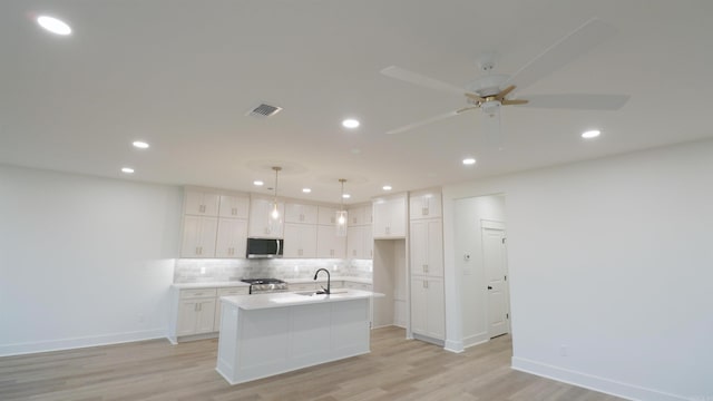 kitchen featuring hanging light fixtures, a center island with sink, stainless steel appliances, and light hardwood / wood-style floors