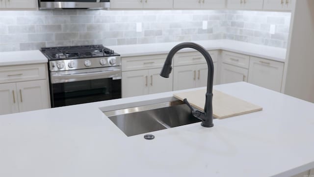 kitchen with decorative backsplash, appliances with stainless steel finishes, white cabinets, and sink