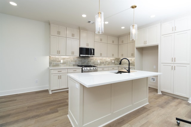 kitchen with appliances with stainless steel finishes, light wood-type flooring, an island with sink, and sink