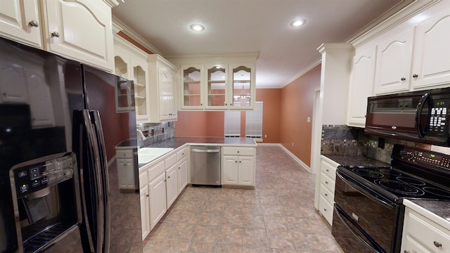 kitchen with crown molding, black appliances, white cabinetry, and backsplash