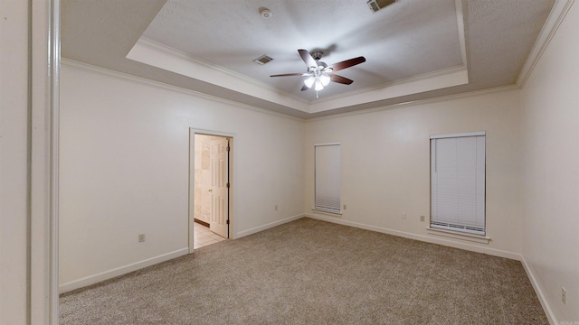 empty room with a raised ceiling, ceiling fan, and light colored carpet