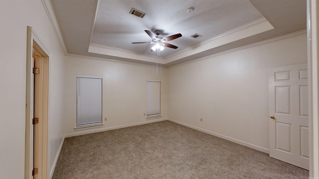 carpeted spare room with crown molding, a tray ceiling, and ceiling fan