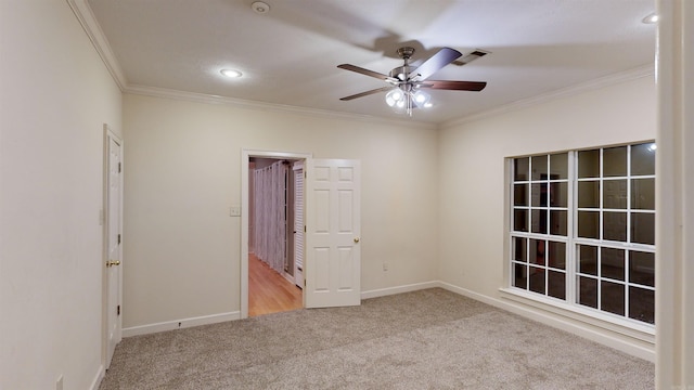 empty room with ceiling fan, light colored carpet, and ornamental molding