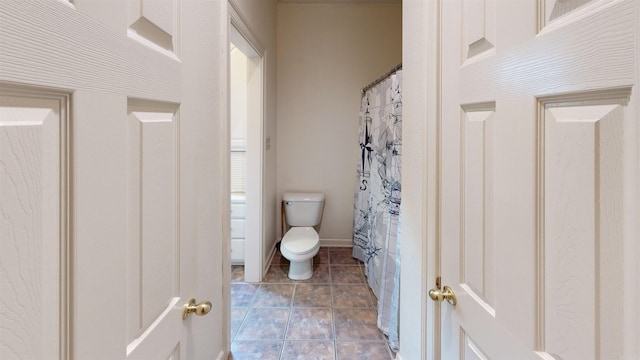 bathroom with curtained shower, tile patterned flooring, and toilet