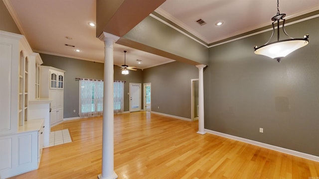 empty room with crown molding, light hardwood / wood-style floors, ceiling fan, and ornate columns