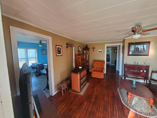 interior space with crown molding, dark hardwood / wood-style floors, ceiling fan, and a wood stove