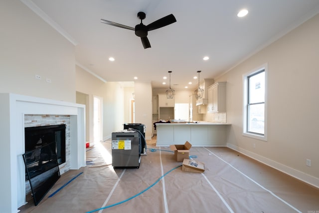 interior space with ceiling fan, a stone fireplace, and crown molding