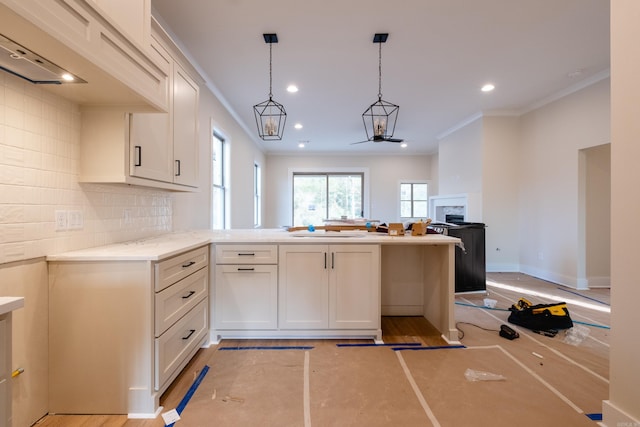 kitchen with ornamental molding, white cabinetry, pendant lighting, and an inviting chandelier