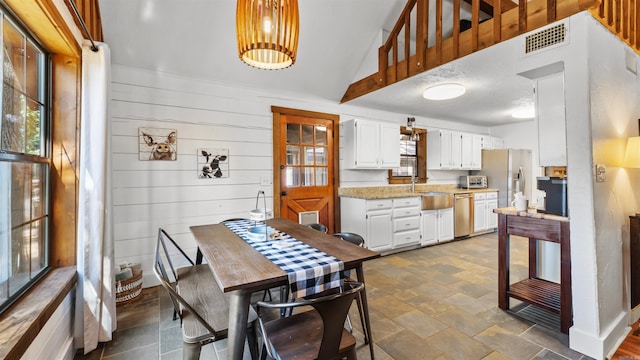 dining room with wooden walls and lofted ceiling