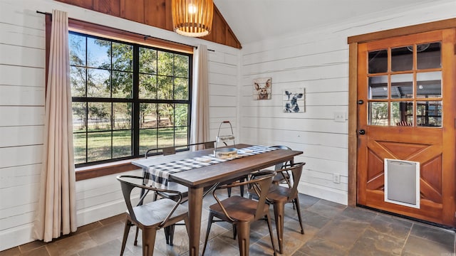 dining space featuring wooden walls and vaulted ceiling