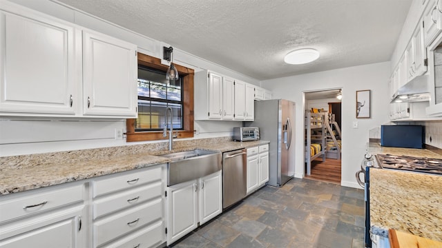 kitchen featuring light stone countertops, stainless steel appliances, white cabinets, and a textured ceiling