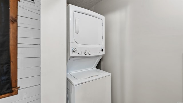 laundry area with stacked washer and clothes dryer and a textured ceiling