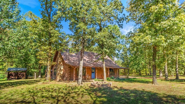 log cabin featuring a storage unit and a front lawn