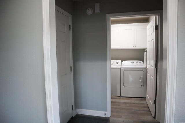 washroom featuring separate washer and dryer, cabinets, and dark wood-type flooring