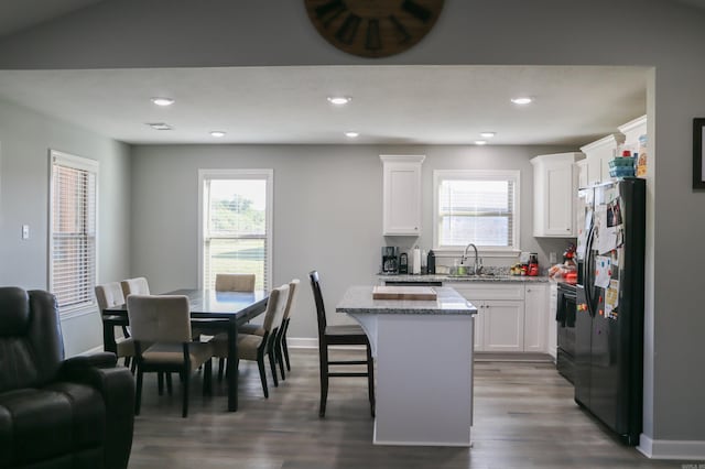 kitchen with black appliances, white cabinetry, a kitchen island, and a wealth of natural light