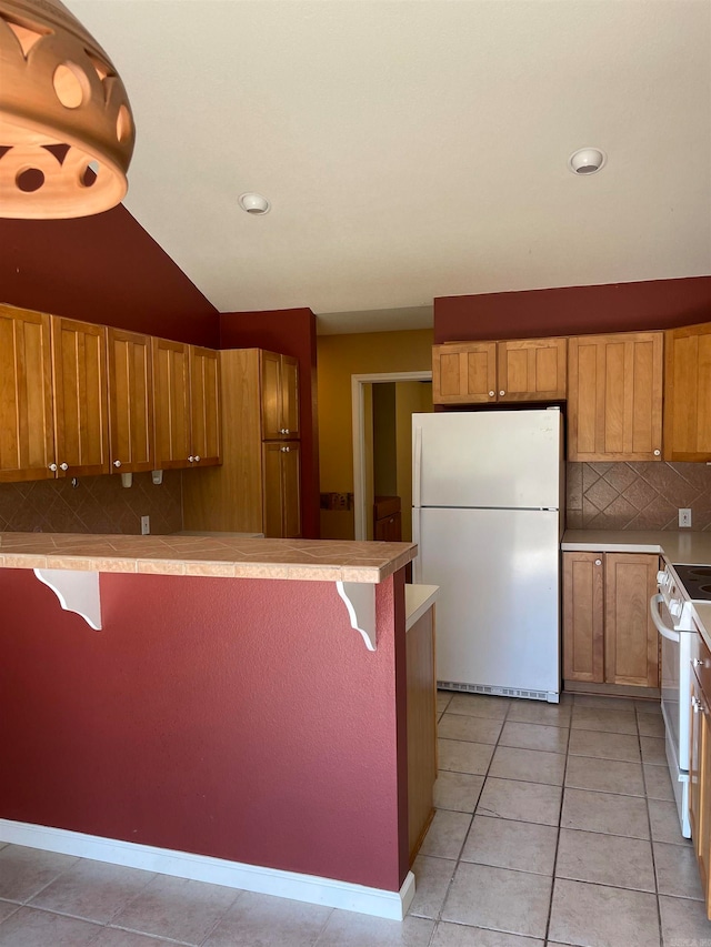 kitchen with backsplash, a breakfast bar, white appliances, light tile patterned floors, and lofted ceiling