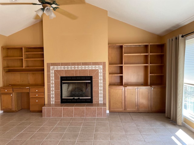 unfurnished living room with ceiling fan, lofted ceiling, a fireplace, and light tile patterned floors