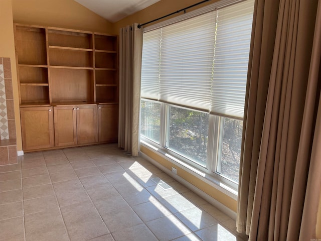 unfurnished room featuring light tile patterned floors and lofted ceiling