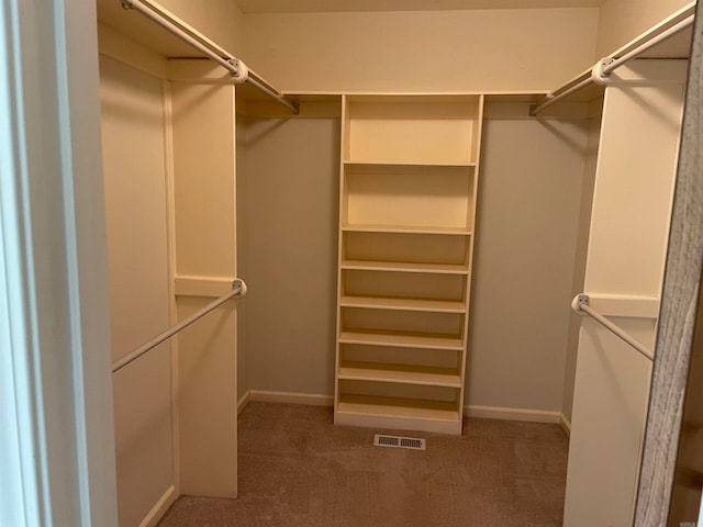 walk in closet with dark colored carpet