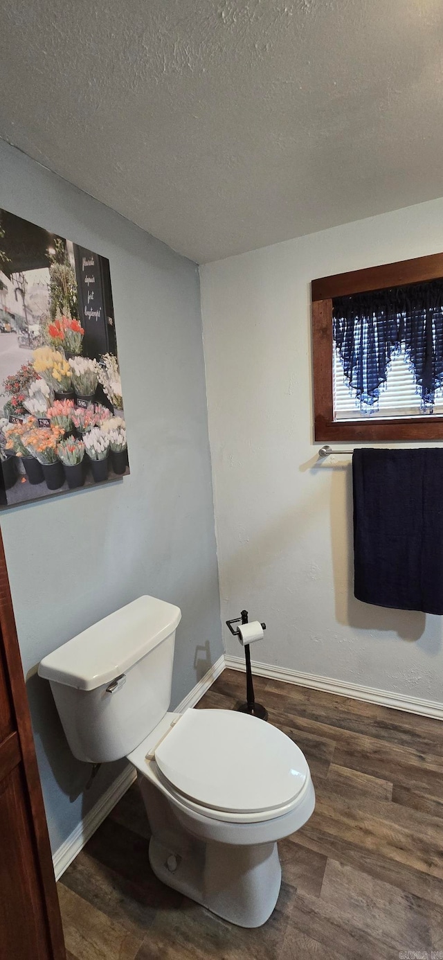 bathroom with wood-type flooring, toilet, and a textured ceiling