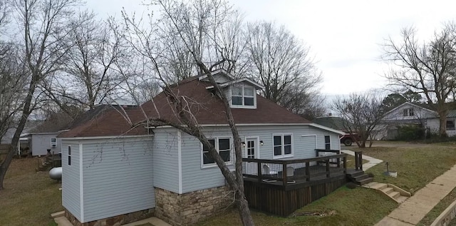 back of property featuring a deck and a lawn