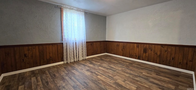 spare room with dark hardwood / wood-style floors and wood walls