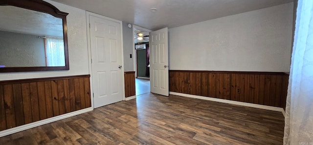 unfurnished room with dark hardwood / wood-style flooring and wood walls