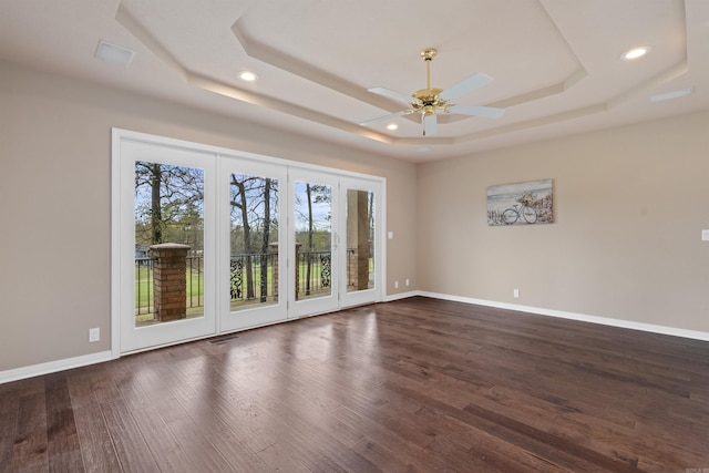 spare room with ceiling fan, a raised ceiling, and dark hardwood / wood-style flooring