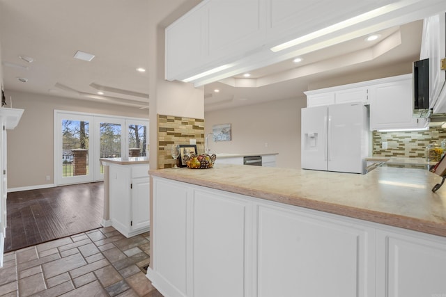 kitchen with white cabinets, white fridge with ice dispenser, a fireplace, and backsplash